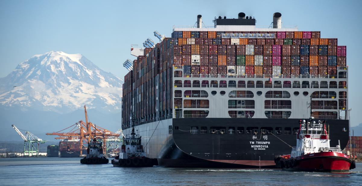 photo of a large containership pulled by a tugboat