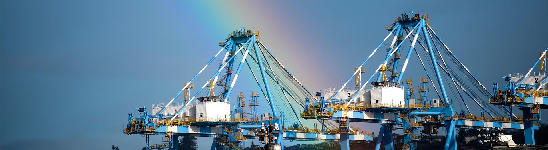 photo of a rainbow over container cranes